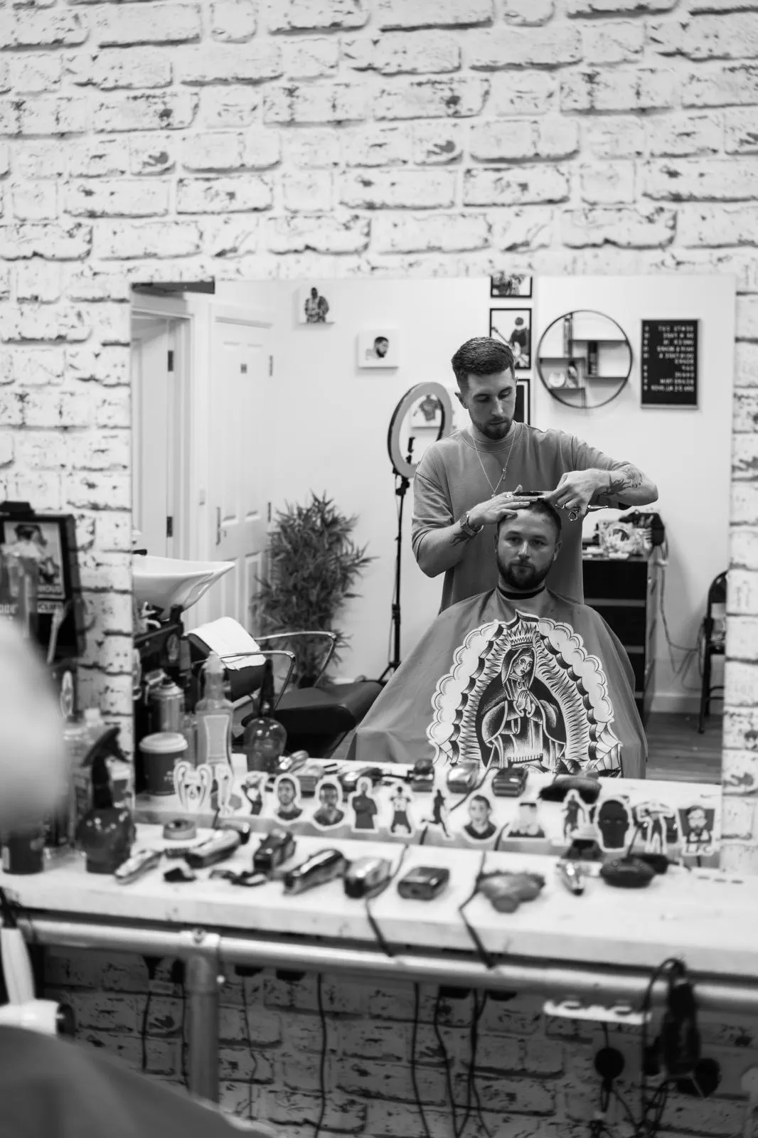 A barber cutting a client's hair, reflected in the mirror at Barber Lounge (black and white)